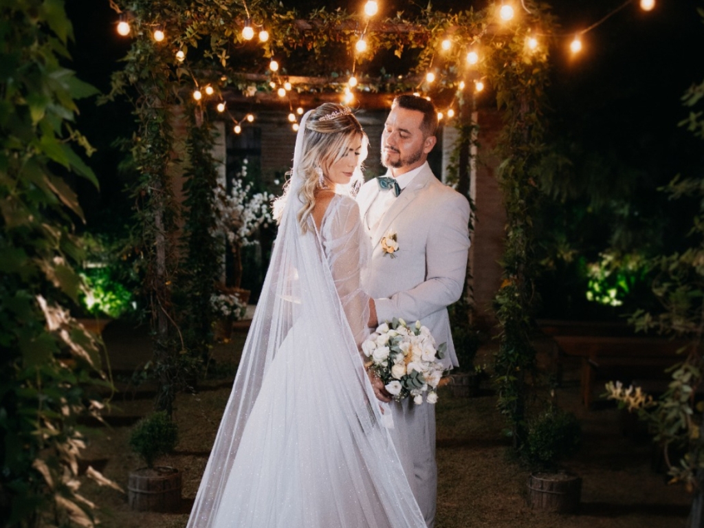 Casal entre folhagens e luzes no jardim