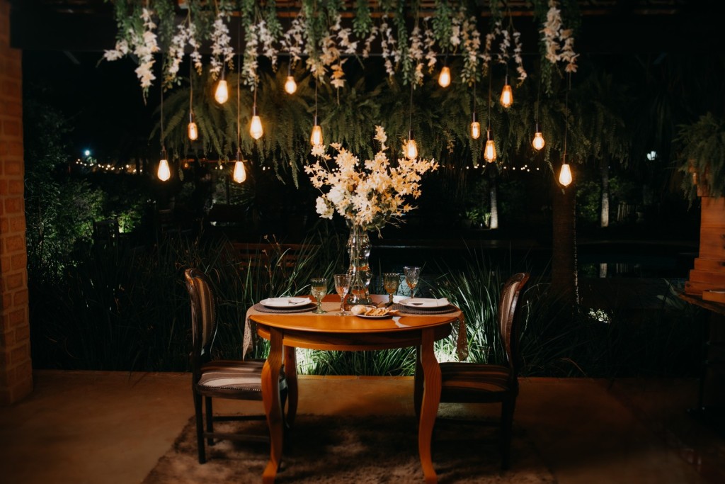 Mesa decorada com flores brancas e luzes suspensas