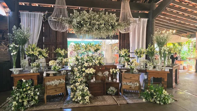 Decoração ampla da mesa de bolo com flores brancas, pendentes, cortinas e móveis de madeira